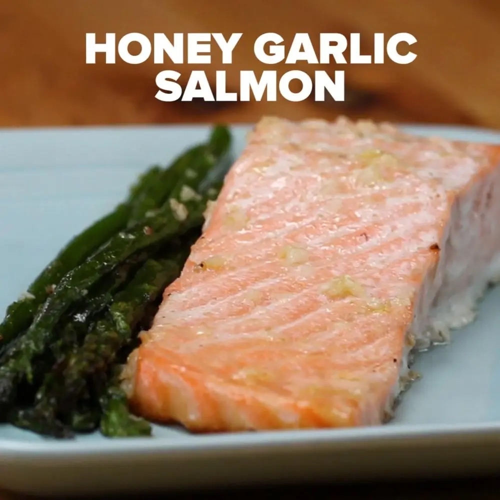 A plate with honey garlic salmon fillet and asparagus. Text above reads &quot;HONEY GARLIC SALMON&quot;