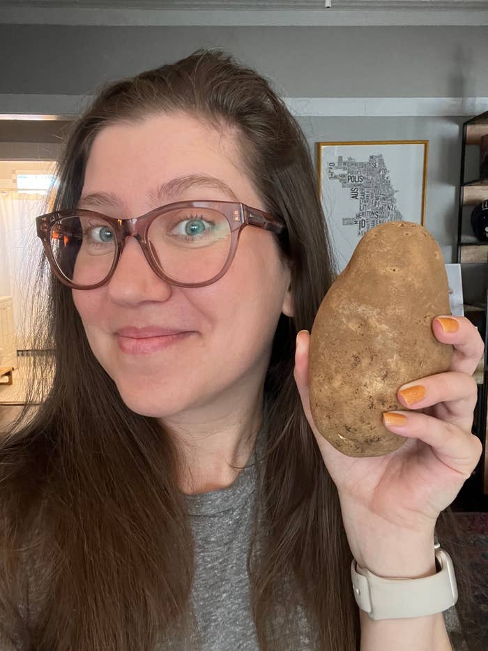 Kelley with glasses smiling and holding a potato